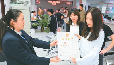 河北省承德市網(wǎng)絡代購經(jīng)營者陳晨(右)從工作人員手中接過帶有統(tǒng)一社會信用代碼的營業(yè)執(zhí)照。 劉環(huán)宇攝(人民圖片)