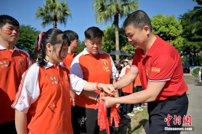 資料圖：廣西華僑實驗高中的教師為高三學(xué)子系上紅絲帶，盼望學(xué)子高考必勝。 俞靖 攝